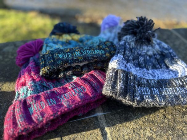 A collection of colourful knitted beanie hats with pom-poms.