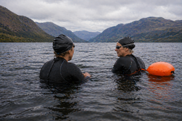 Open water swimming coach speaking with a beginner swimmer in a Scottish loch during a 1:1 coaching session